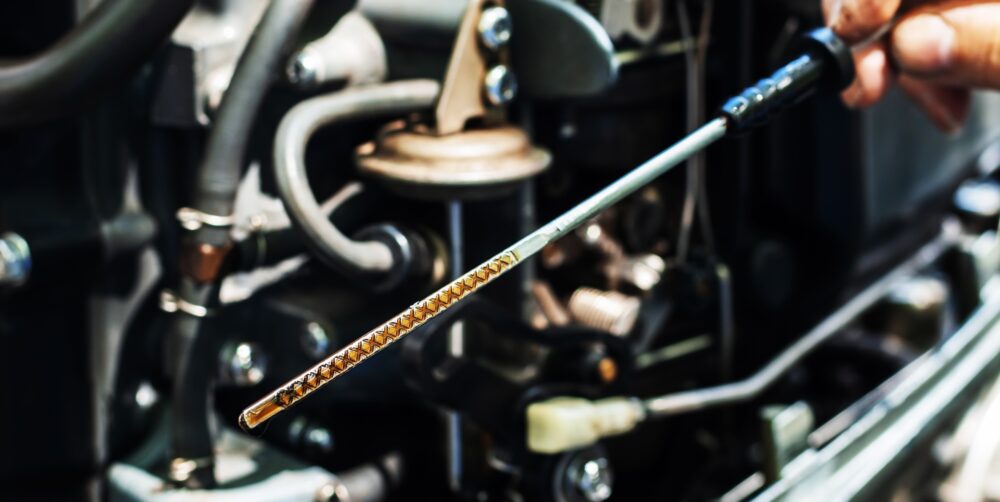 Checking the oil level in the boat engine. A dipstick with marks and an oil injector in the hands of a technical master. Close-up. unrecognizable person